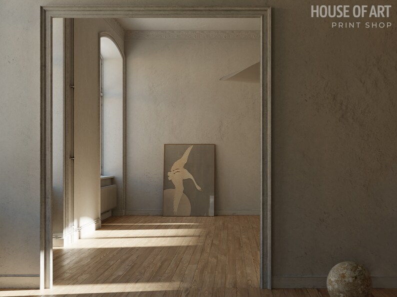 Op de afbeelding: Een minimalistisch interieurontwerp met een grote, ingelijste abstracte kunstprint op een lichtgrijze muur. De kamer heeft een houten vloer en een groot raam met natuurlijk licht dat naar binnen stroomt.
