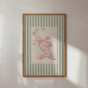 May include: A framed floral print featuring a branch with pink blossoms and green leaves. The artwork is set against a cream-colored background within a rectangular frame, surrounded by a green and white striped border. The frame is a light brown color. The text "HOUSE OF ART PRINT SHOP" is at the bottom.