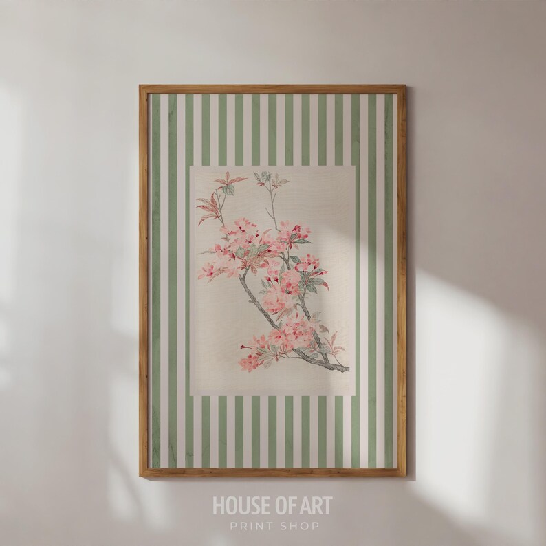 May include: A framed floral print featuring a branch with pink blossoms and green leaves. The artwork is set against a cream-colored background within a rectangular frame, surrounded by a green and white striped border. The frame is a light brown color. The text "HOUSE OF ART PRINT SHOP" is at the bottom.