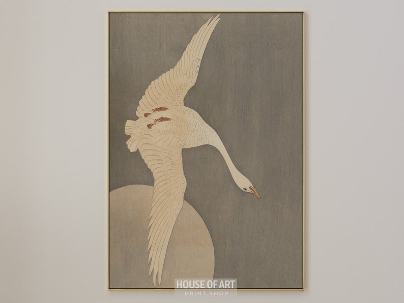 Op de afbeelding: Een witte vogel met uitgespreide vleugels vliegt tegen een grijze achtergrond. De vleugels van de vogel zijn wijd uitgespreid en zijn kop is naar beneden gekanteld. De achtergrond is een gedempt grijs, met een vleugje bruin. De vogel is scherp in focus, terwijl de achtergrond licht wazig is. De afbeelding is een traditionele Japanse houtsnede.
