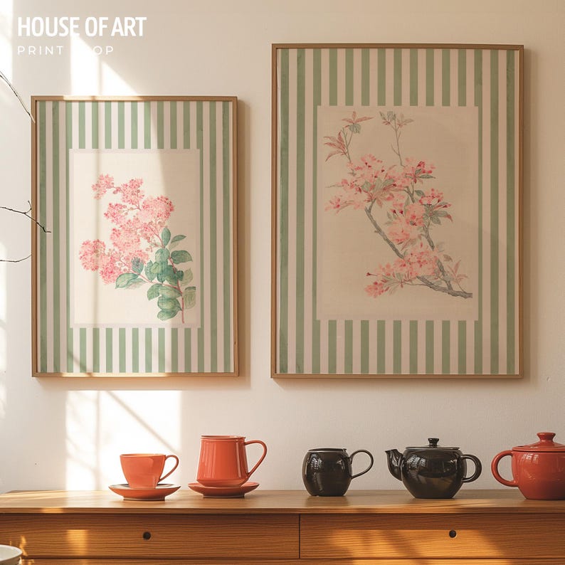 May include: Two framed floral prints with pink flowers and green leaves, set against a striped background. The prints are displayed above a wooden table with orange teacups, saucers, and teapots. The text "HOUSE OF ART PRINT SHOP" is visible.