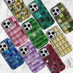 Puede incluir: Una colección de fundas para teléfonos de estilo mosaico en varios colores, incluyendo verde, rosa, azul, morado y rojo. Cada funda presenta un patrón de cuadrícula de pequeñas baldosas cuadradas, creando una apariencia texturizada. Las fundas están diseñadas para un smartphone con cámara de triple lente.