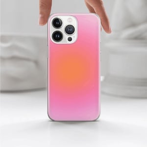 May include: A clear phone case with a pink to orange gradient. The case has a raised camera bump with three lenses.