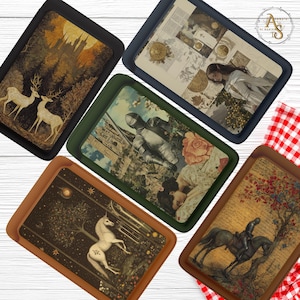 Op de afbeelding: Een verzameling decoratieve trays met diverse artistieke ontwerpen. De trays tonen afbeeldingen van herten, een kasteel, een ridder, een eenhoorn en een ruiter op een paard. Elke tray heeft een gekleurde rand, waaronder zwart, blauw, groen en bruin.