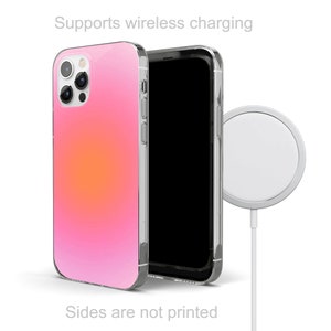 May include: A pink and orange gradient phone case with a clear back and a wireless charging symbol. The case is compatible with wireless charging.