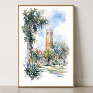 May include: A vertical watercolor painting in a wooden frame depicting a tall, orange-toned brick clock tower rising above lush green trees and palm plants. The scene features a bright blue sky with soft clouds and a path leading toward the building.