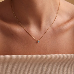 Puede incluir: Un collar de cadena de oro con un peque&ntilde;o colgante de coraz&oacute;n azul.
