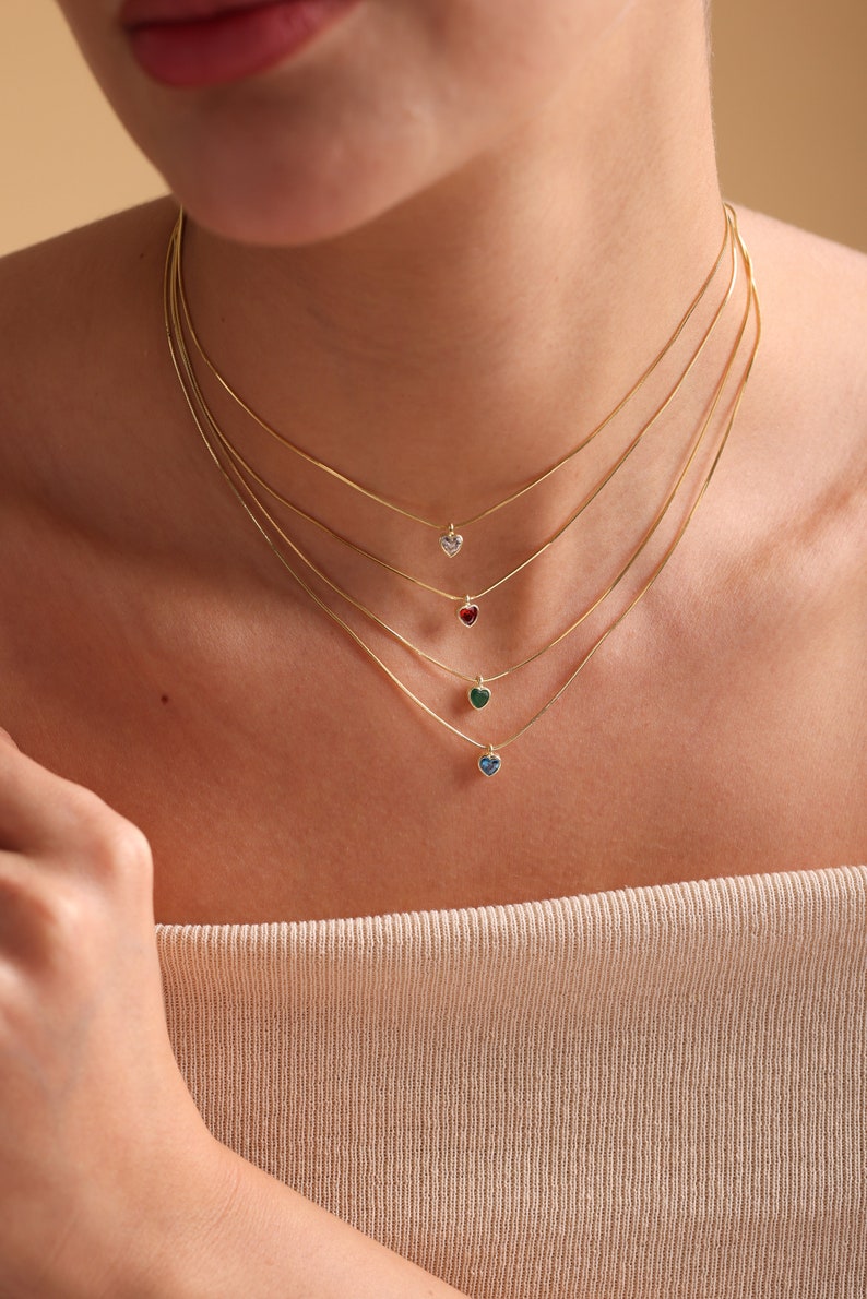 Puede incluir: Cuatro collares de cadena de oro con colgantes en forma de coraz&oacute;n. Los colgantes son de diferentes colores: transparente, rojo, verde y azul.