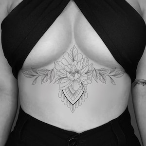 Puede incluir: Diseño de tatuaje floral en blanco y negro en el pecho. El tatuaje presenta una flor grande con pétalos y hojas detallados, y una forma geométrica decorativa. El diseño es centrado y simétrico.