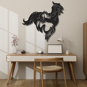 Peut inclure: Une décoration murale en métal noir représentant la silhouette stylisée de deux chevaux, l'un debout et un plus petit devant, avec des crinières et des queues fluides, fixée sur un mur uni au-dessus d'un bureau et d'une chaise en bois.