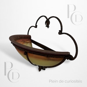 May include: An antique wall sconce with a brown metal frame and a bowl-shaped glass shade. The shade transitions from a warm yellow to a reddish-brown hue. The sconce has decorative flourishes and the text "Plein de curiosités".