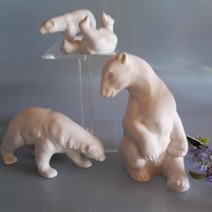 Könnte beinhalten: Drei weiße Keramik-Eisbärfiguren in verschiedenen Posen. Einer steht aufrecht, ein anderer krabbelt und der dritte liegt auf dem Rücken. Die Figuren stehen auf einer hellgrauen Oberfläche.