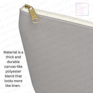 Op de afbeelding: Close-up van een grijze canvas-achtige polyester blend pouch met een gouden rits. Het materiaal is dik en duurzaam, lijkend op linnen. De tekst op de pouch luidt "Live Laugh Love Party".