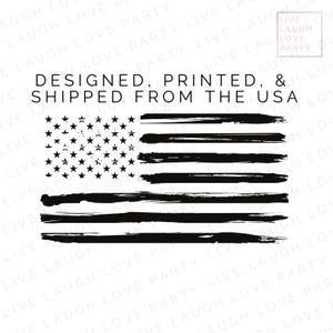 Op de afbeelding: Zwart-wit ontwerp van de Amerikaanse vlag met een distressed penseelstrekeffect. De vlag heeft sterren en strepen, met de tekst "DESIGNED, PRINTED, & SHIPPED FROM THE USA". Het ontwerp staat op een witte achtergrond.