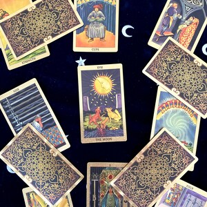 May include: Tarot card spread with ten cards, including The Moon, The High Priestess, Nine of Cups, Nine of Swords, Strength, Four of Swords, Three of Wands, and three cards with ornate gold designs.