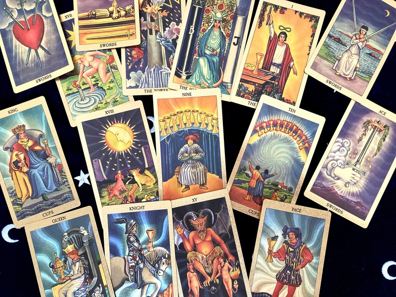May include: A spread of tarot cards on a black velvet surface. The cards feature colorful illustrations and text, including "KING", "SWORDS", "THE TOWER", "THE NINE", "TEN", "ACE", "CUPS", "QUEEN", "KNIGHT", "J", "THE", and "CUPS".
