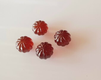 May include: Four brown, round, hard candies with a starburst design. The candies are on a white surface.