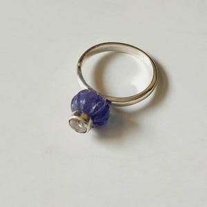 May include: A silver ring with a carved purple gemstone set in the center.