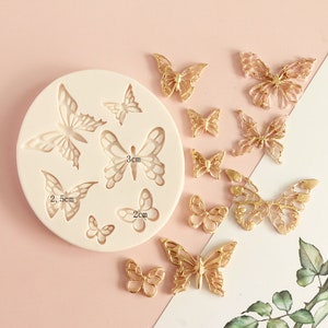 May include: Silicone mold with 10 butterfly shapes, including a 3 cm butterfly, a 2.5 cm butterfly, and a 2 cm butterfly. The mold is shown next to 10 gold-colored butterfly decorations.