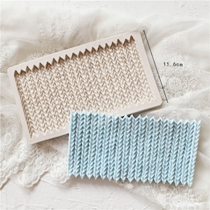 May include: A white silicone mould with a textured pattern resembling a knitted fabric. The mould is 11.6 cm long and is shown next to a blue silicone mould with the same pattern.