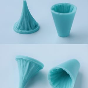 May include: Four light blue, cone-shaped objects. Two are upright, and two are inverted. The objects have a textured, ruffled appearance. The text at the bottom reads: H: 25 L: 30MM.