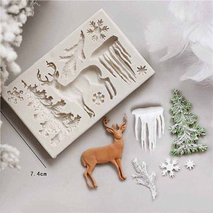 May include: A white silicone mold with a reindeer, a Christmas tree, snowflakes, and icicles. The mold is 7.4 inches wide. There are also several finished decorations made from the mold, including a brown reindeer, a green Christmas tree, and white icicles.