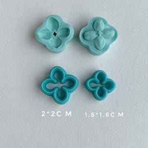 May include: Four aqua-colored flower-shaped molds and cutters. Two molds have a flower impression, and two are cutters. The text on the image reads "2*2C M" and "1.6*1.6C M". These tools are likely for crafting or baking.