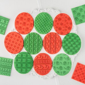 May include: A set of 12 Christmas-themed silicone stamps for baking and decorating. The stamps feature various designs, including snowflakes, trees, presents, and candy canes. The stamps are arranged in a circle on a white surface.