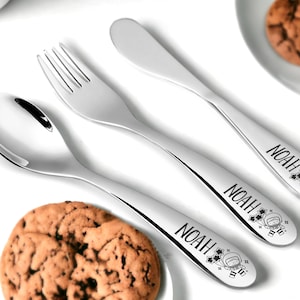 Peut inclure: Un ensemble de trois couverts argentés pour enfant, comprenant une cuillère, une fourchette et un couteau à beurre. Chaque couvert porte le nom "Noah" gravé sur le manche, ainsi qu'un petit dessin d'astronaute.