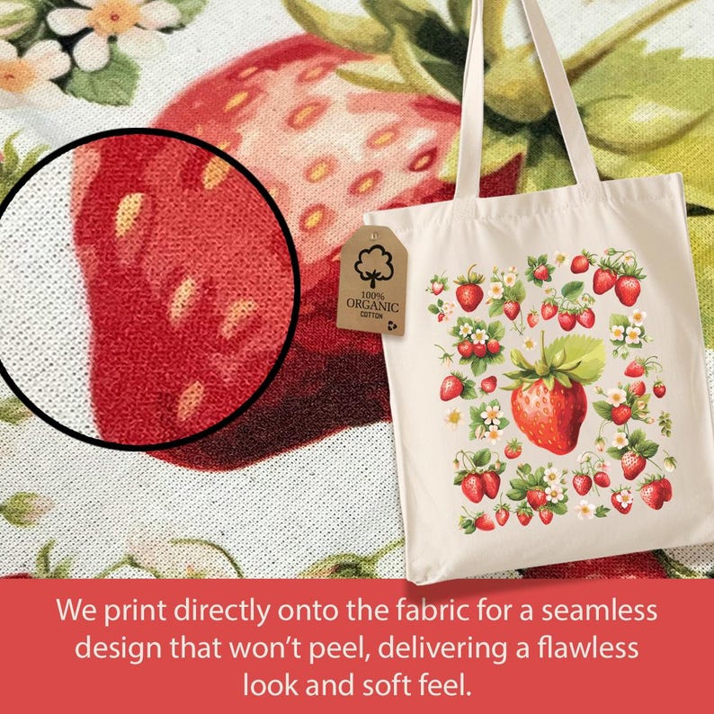 May include: A white canvas tote bag with a design of red strawberries and white flowers. The bag has two handles and a label that says "100% Organic Cotton".