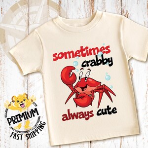 May include: A white t-shirt with a red cartoon crab and the text "sometimes crabby always cute".