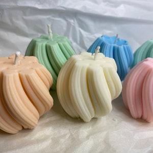 May include: Five decorative candles in various pastel colors, each with a unique swirl design. The candles are arranged on a white surface.