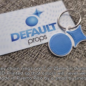 May include: A blue and white 3D printed keychain with a ring. The keychain features a circle and a star shape. The text "DEFAULT props" is visible on a white card behind the keychain.
