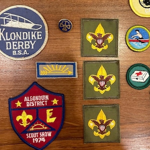 May include: A collection of vintage Boy Scout patches, including a yellow Muscoot District Camporee patch, a green Algonquin District Scout Show patch, and a green Suffolk County Jamboree patch.