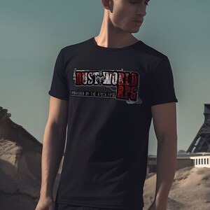 K&ouml;nnte beinhalten: Ein schwarzes T-Shirt mit einem wei&szlig;en Grafikdruck, auf dem "DUST WORLD 2PS" in einer roten und wei&szlig;en Schrift steht. Das Shirt wird von einer Person getragen, die vor dem Eiffelturm steht.