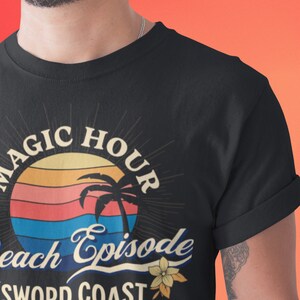 Pode incluir: Camiseta preta com um gr&aacute;fico de p&ocirc;r do sol retr&ocirc; e o texto "Magic Hour Beach Episode Sword Coast Fantasy DND Beach".