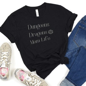 May include: Black t-shirt with white text that reads "Dungeons Dragons Mom Life" and a white 20-sided die graphic.