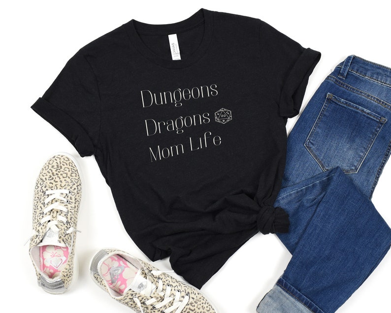 May include: Black t-shirt with white text that reads "Dungeons Dragons Mom Life" and a white 20-sided die graphic.