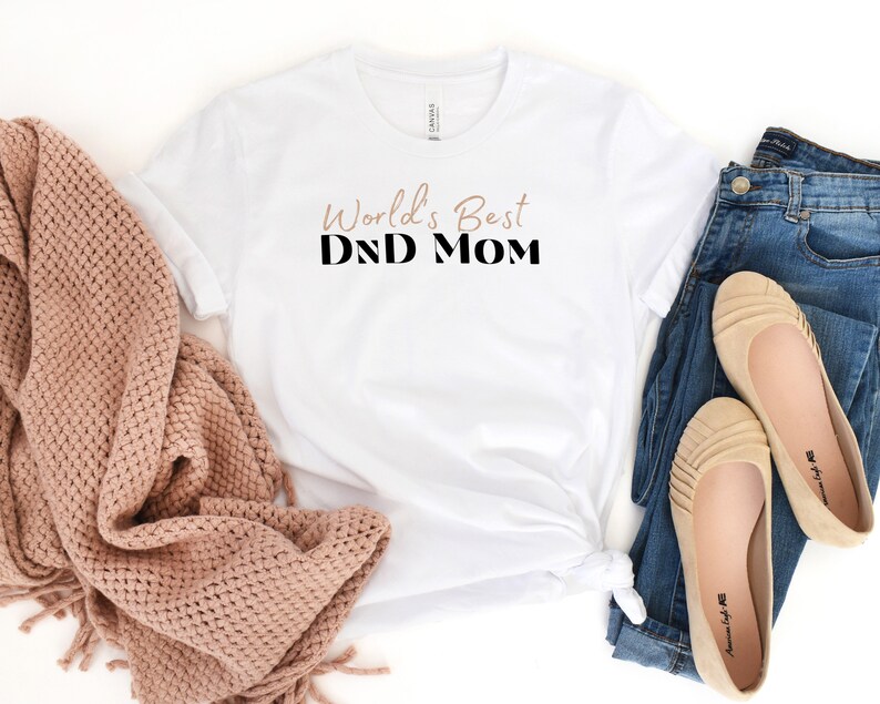May include: White t-shirt with the text "World's Best DND Mom" in black and brown lettering.