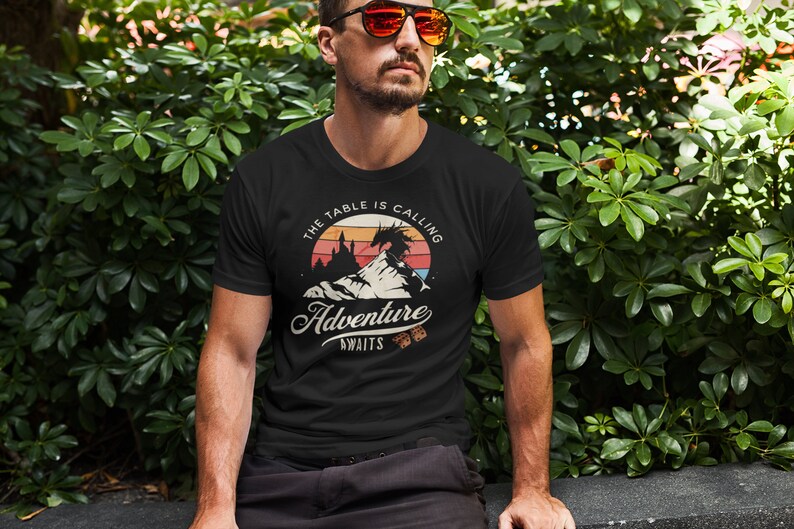 The table is calling adventure awaits dnd t-shirt design on a cool man with sunglasses in front of a bush