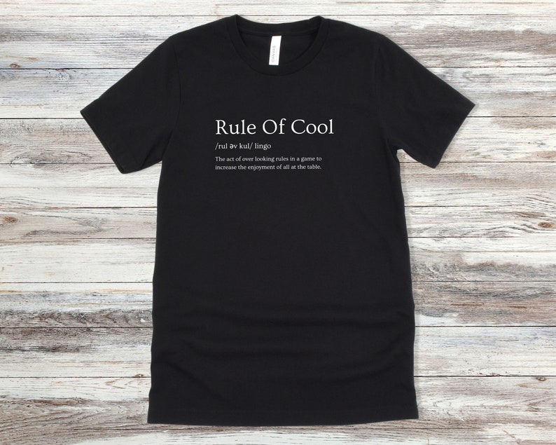 May include: Black t-shirt with white text that reads "Rule Of Cool /rul av kul/ lingo The act of over looking rules in a game to increase the enjoyment of all at the table."