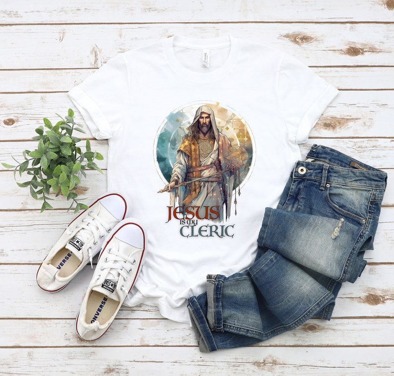 May include: White t-shirt with a graphic of Jesus in a robe holding a sword. The text "Jesus is my Cleric" is printed below the graphic.