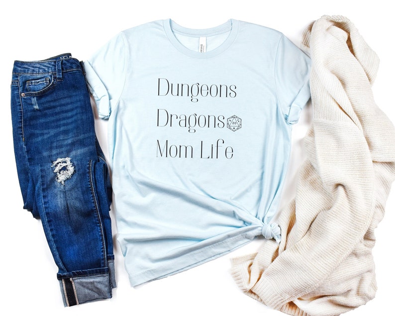 May include: A light blue t-shirt with the text "Dungeons Dragons Mom Life" and a Dungeons and Dragons dice symbol.