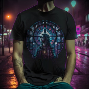May include: A black t-shirt with a colorful stained glass window design featuring a man with long hair and a beard. The design is centered on the shirt and is surrounded by a black background.