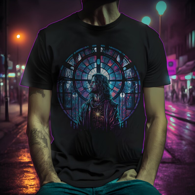 May include: A black t-shirt with a colorful stained glass window design featuring a man with long hair and a beard. The design is centered on the shirt and is surrounded by a black background.