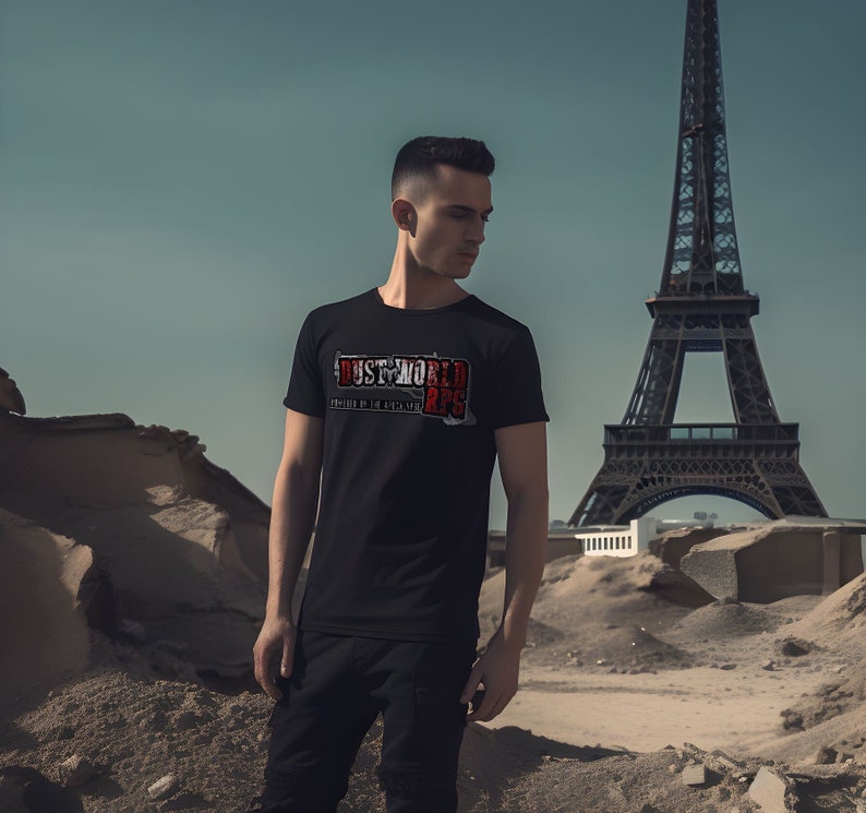 K&ouml;nnte beinhalten: Ein schwarzes T-Shirt mit einem wei&szlig;en Grafikdruck, auf dem "DUST WORLD 2PS" in einer roten und wei&szlig;en Schrift steht. Das Shirt wird von einer Person getragen, die vor dem Eiffelturm steht.