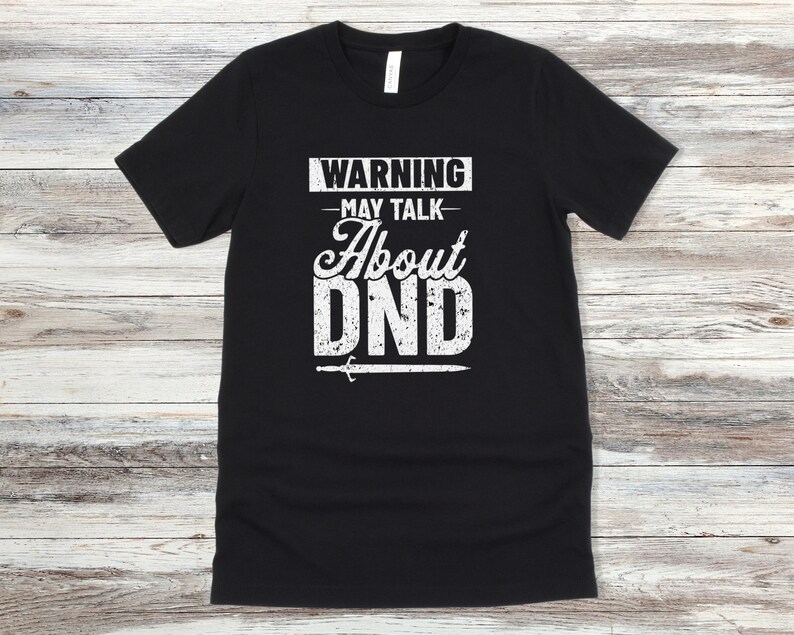 May include: Black t-shirt with white text that reads "WARNING - MAY TALK ABOUT DND" with a sword graphic below the text.