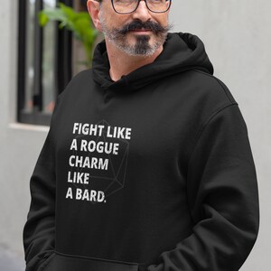 May include: Black hooded sweatshirt with the text "Fight like a rogue, charm like a bard." printed in white on the front. The text is surrounded by a stylized graphic of a twenty-sided die.