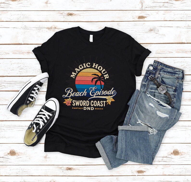 Pode incluir: Camiseta preta com um gr&aacute;fico de p&ocirc;r do sol retr&ocirc; e o texto "Magic Hour Beach Episode Sword Coast Fantasy DND Beach".