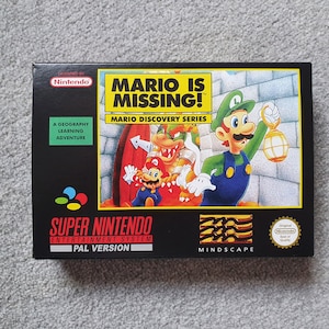 May include: A black rectangular Super Nintendo Entertainment System game box for Mario Is Missing! featuring Luigi holding a lantern, Mario, and Bowser. The box includes the text Mario Discovery Series, A Geography Learning Adventure, and a Nintendo seal.